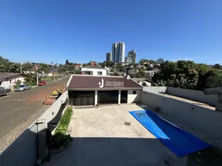 Vista externa de uma propriedade com área pavimentada e cerca.