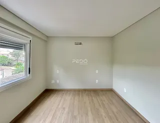 Ambiente interno de uma sala com piso de madeira clara e grande janela.