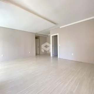 Ambiente interno amplo com piso de madeira clara e paredes brancas.