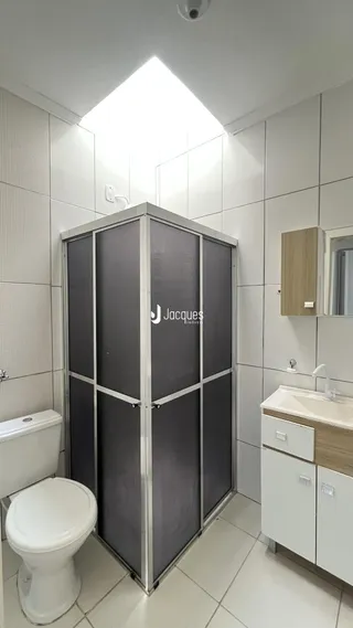 Foto de um banheiro com box de vidro e azulejos brancos.