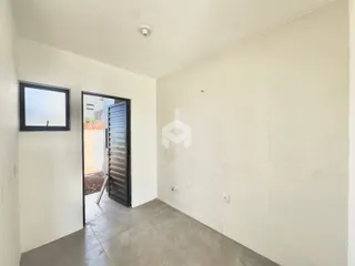 Interior de um corredor com paredes brancas e piso de concreto.