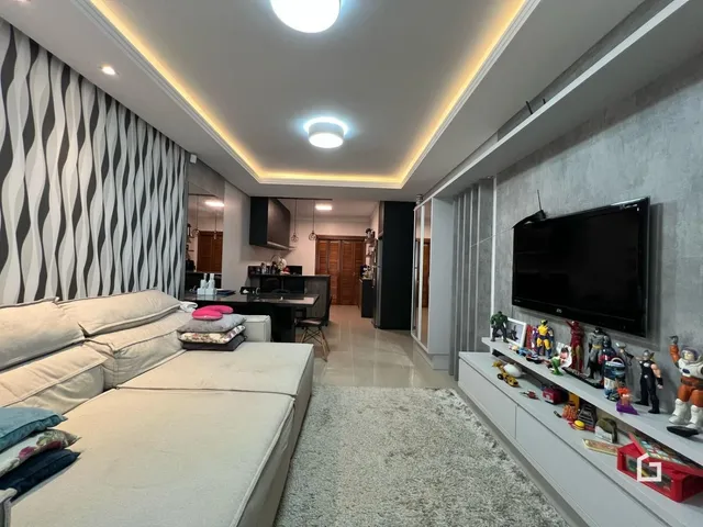 Sala de estar moderna com sofá e televisão em um apartamento no Brasil.