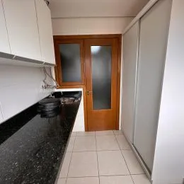 Foto de uma cozinha com armários brancos e bancada escura.