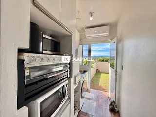 Vista interna da cozinha com forno e acesso a uma área externa com jardim.