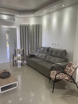 Sala de estar moderna com sofá cinza e cadeiras decorativas.