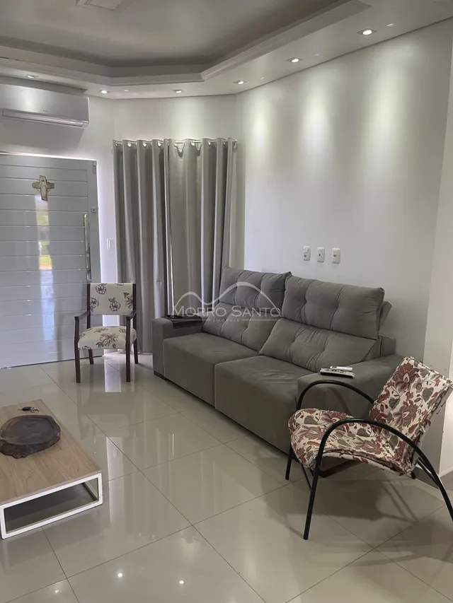 Sala de estar moderna com sofá cinza e cadeiras decorativas.