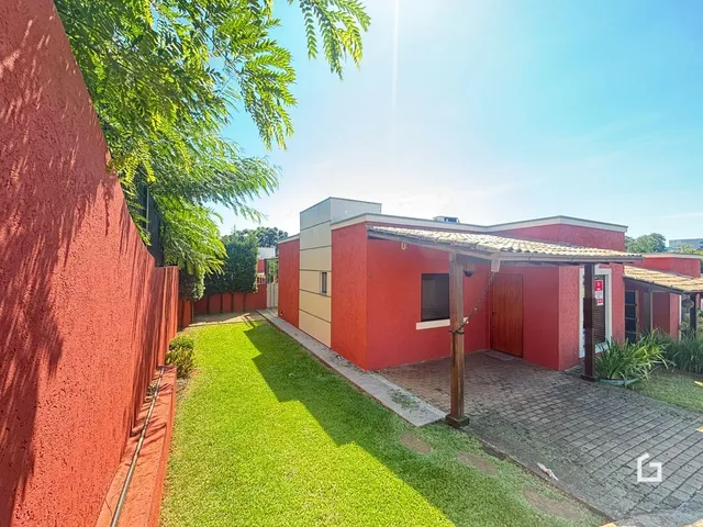 Vista externa de uma propriedade com jardim verde e parede vermelha.