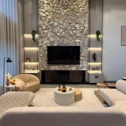 Foto de uma sala de estar com uma parede de pedra e televisão.