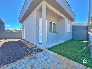 Fachada externa de uma residência moderna com jardim e área pavimentada.