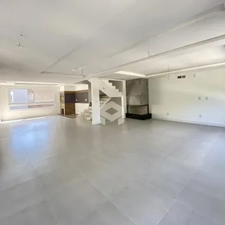 Ambiente interno amplo com piso de cerâmica clara e pé direito alto.