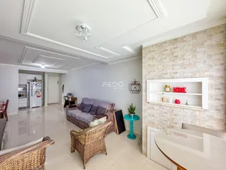 Sala de estar com piso claro e parede de destaque em pedra na residência.
