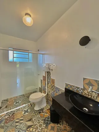 Foto de um banheiro com piso de azulejos decorativos e vaso sanitário branco.