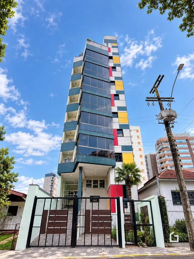 Fachada de um prédio residencial alto com revestimento de vidro e cores vibrantes.
