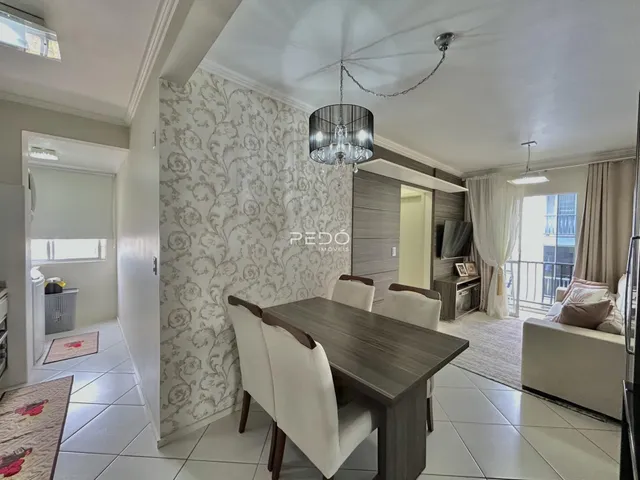Foto de uma sala de jantar com mesa de madeira escura e parede com papel de parede floral.