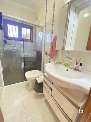 Foto de um banheiro com louças sanitárias brancas e piso de cerâmica.