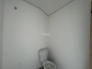 Foto de uma parede branca em um ambiente interno com um vaso sanitário.
