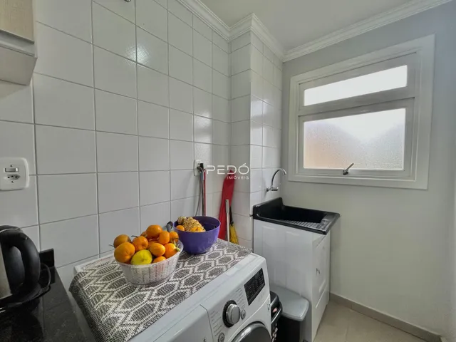 Interior de uma cozinha com azulejos brancos e uma janela.