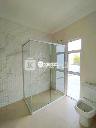Foto de um banheiro com box de vidro e vaso sanitário branco.