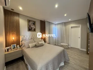 Quarto com cama grande e decoração neutra, apresentando painéis de madeira na cabeceira.