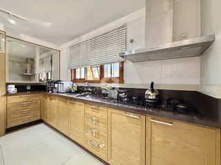 Cozinha moderna com armários de madeira clara e bancada escura.