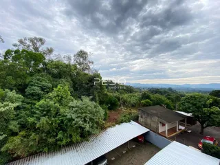 Vista externa da propriedade cercada por vegetação densa e colinas.