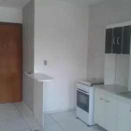 Vista interna de uma área com bancada e eletrodomésticos brancos.