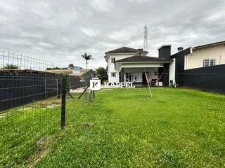 Fachada de uma residência com gramado verde e cerca na propriedade em Lajeado.