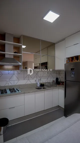 Interior da cozinha com armários brancos e eletrodomésticos de aço inoxidável.