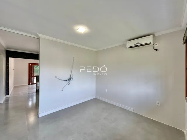 Interior de uma sala com paredes brancas e piso claro.