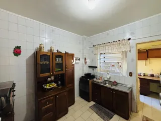 Interior de uma cozinha com armários de madeira e piso de cerâmica.