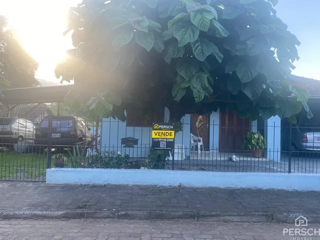 Foto da fachada de uma residência em Lajeado, Brasil, parcialmente obscurecida por folhagem.