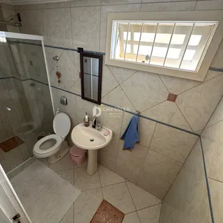 Foto interna de um banheiro com azulejos e box de vidro.