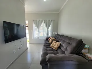 Sala de estar com sofá cinza e televisão montada na parede.