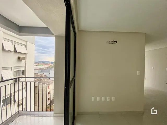 Vista de um corredor interno com porta de vidro e varanda.