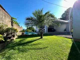 Vista externa de uma propriedade com gramado e piscina ao ar livre.