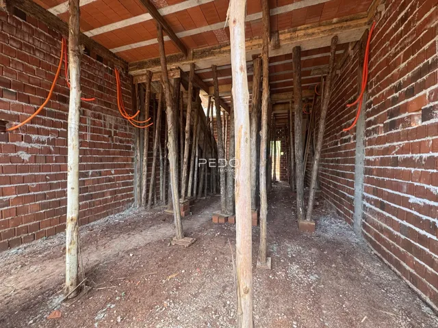 Corredor interno com paredes de tijolo e vigas de madeira expostas.