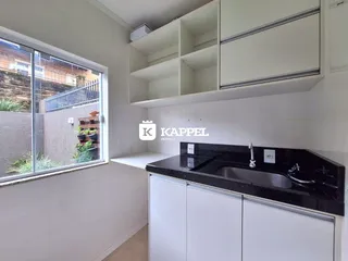 Cozinha com bancada escura e janela com vista externa.