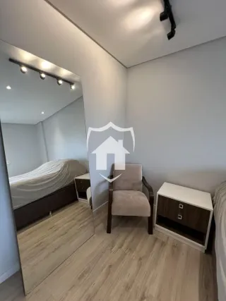 Quarto com piso de madeira e espelho refletindo o ambiente.
