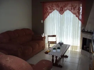 Sala de estar com um sofá marrom e cortinas claras.