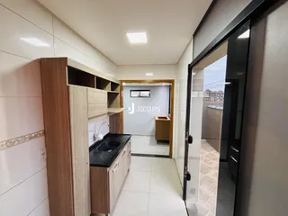 Vista interna de uma cozinha com armários de madeira e piso cerâmico claro.