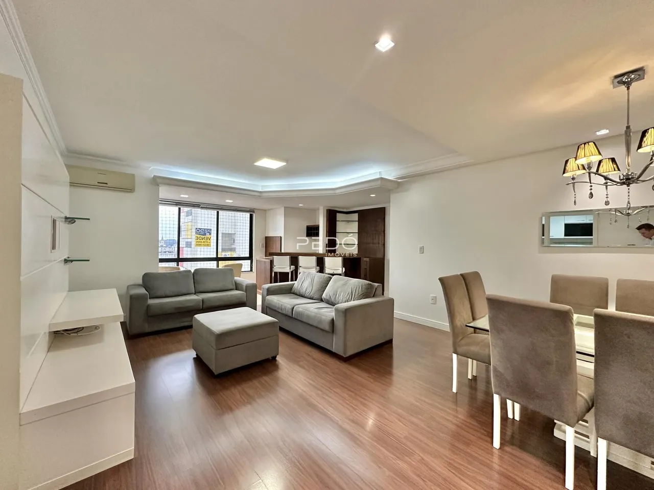 Sala de estar com piso de madeira e sofás modernos.