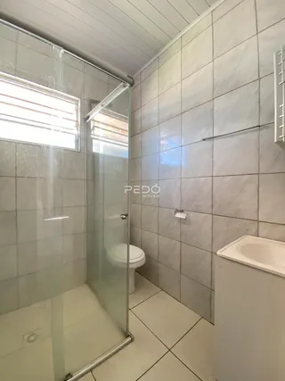 Banheiro com revestimento de cerâmica e box de vidro.