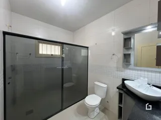 Imagem de um banheiro com box de vidro e azulejos brancos.