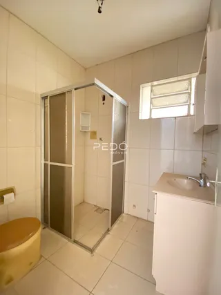 Foto de um banheiro com revestimento cerâmico e box de vidro.