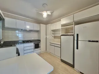 Vista da cozinha moderna com armários brancos e piso de madeira clara.
