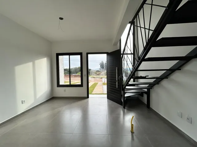 Interior de uma sala com piso de cerâmica e escadaria moderna.