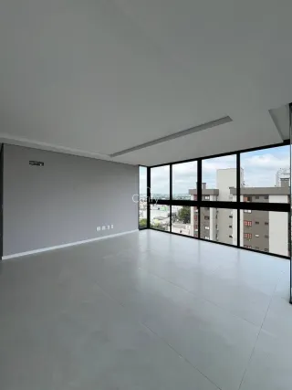Sala ampla com piso de concreto e grandes janelas que proporcionam uma vista urbana.