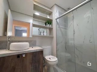 Foto de um banheiro com box de vidro e louças sanitárias.