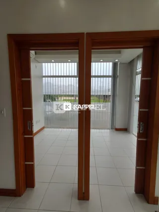 Hall de entrada com piso claro e molduras de madeira visíveis.