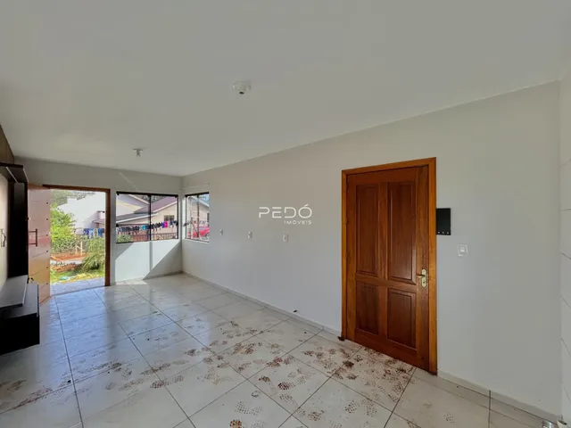 Sala de estar com piso de cerâmica e porta de madeira em uma residência.